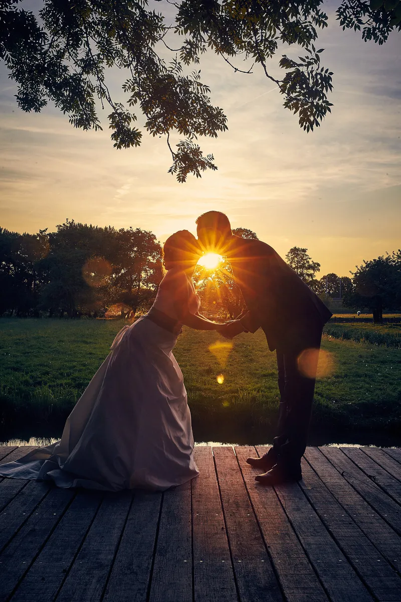 Linsey en Tim kussen als silhouet in de ondergaande zon op de steiger