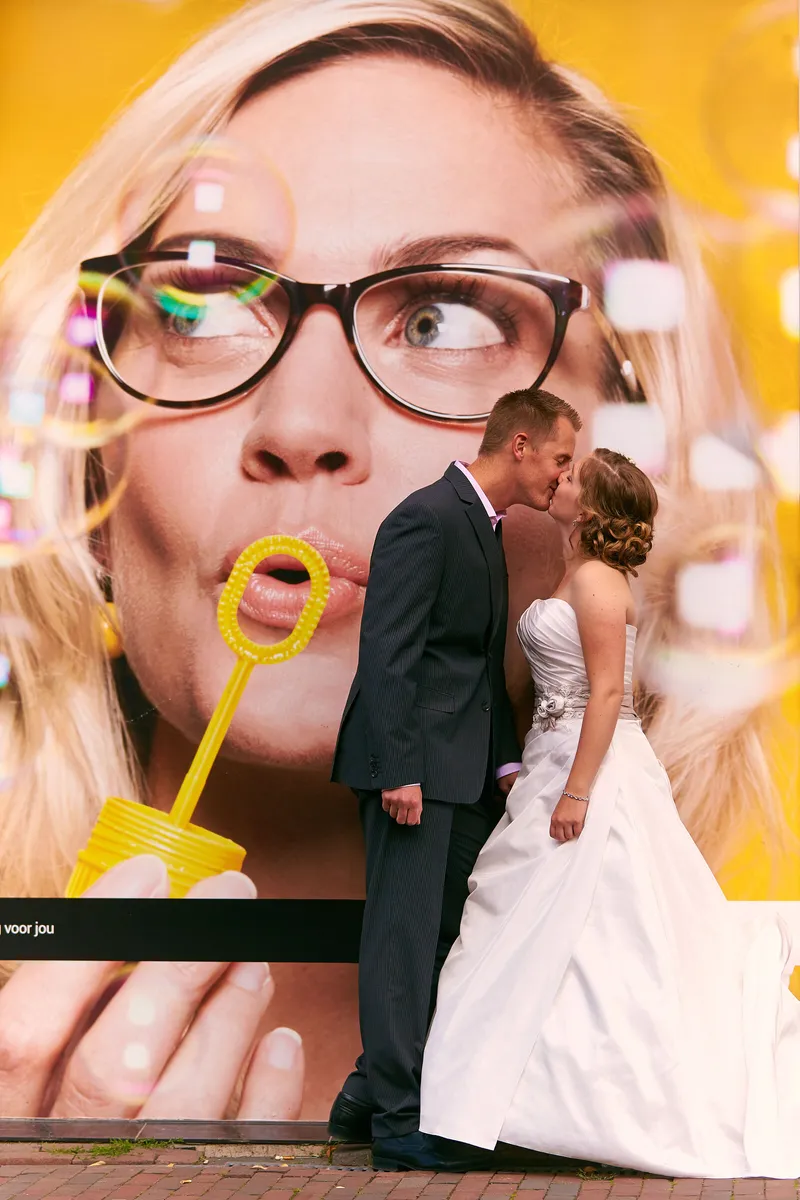 Linsey en Tim kussen voor een reclamebord met een vrouw die bellen blaast