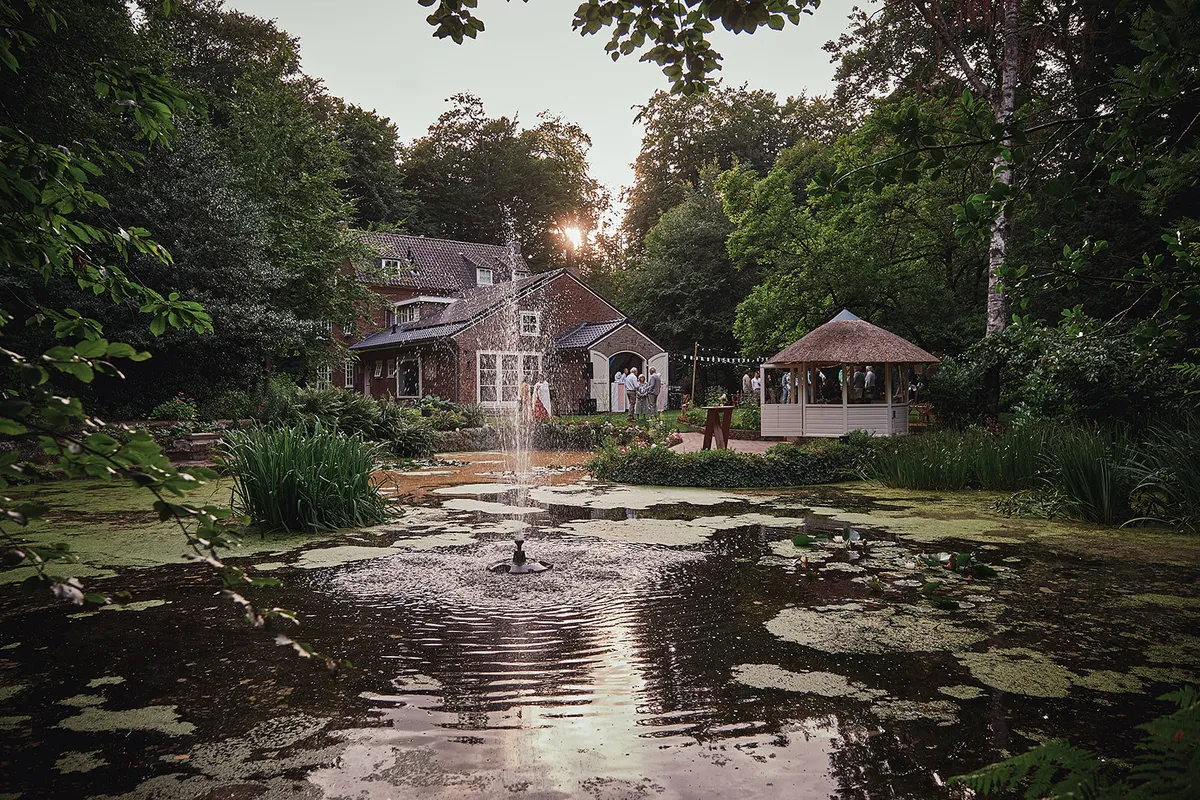 De vijver met fontein en het prieel voor het huis in het avondlicht