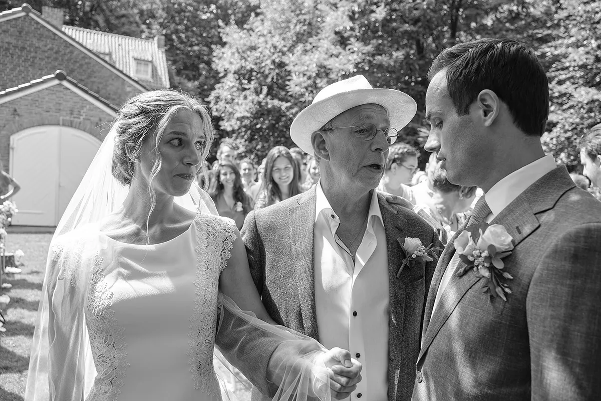 Zwart-wit: Kariens vader brengt haar naar Niels, gasten kijken toe