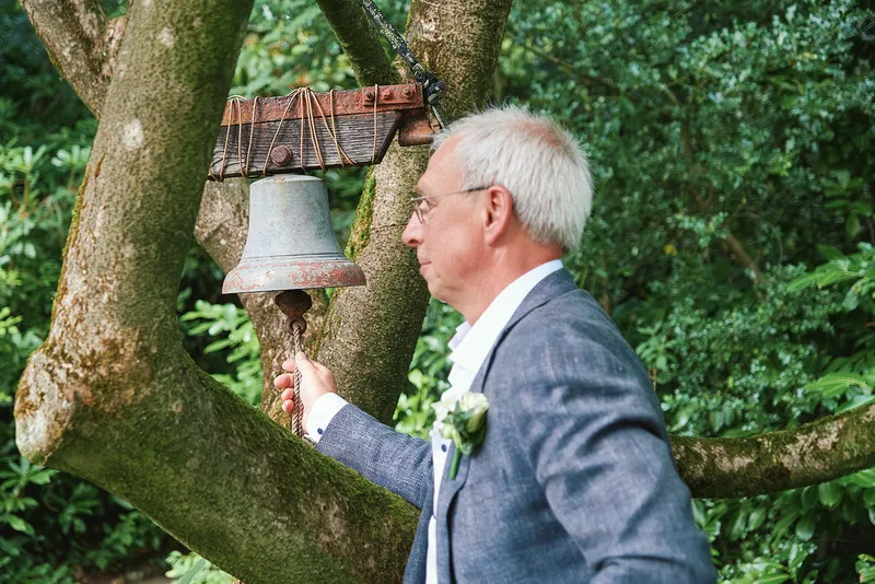 Kariens vader luidt de klok in de boom bij de ceremonie