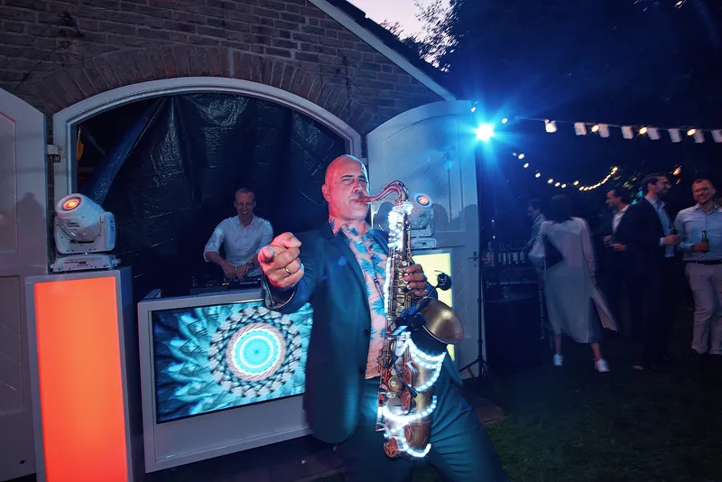 De saxofonist speelt met overgave in het licht van de dj-booth