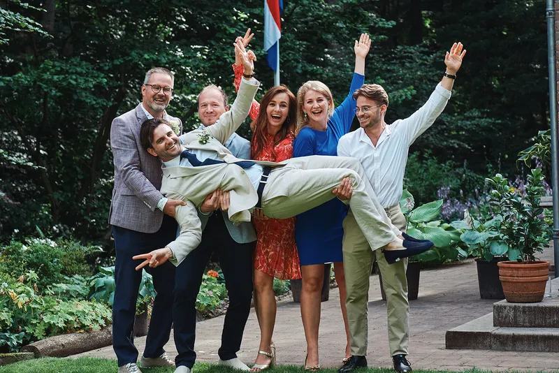 Vrienden tillen lachend een gast de lucht in