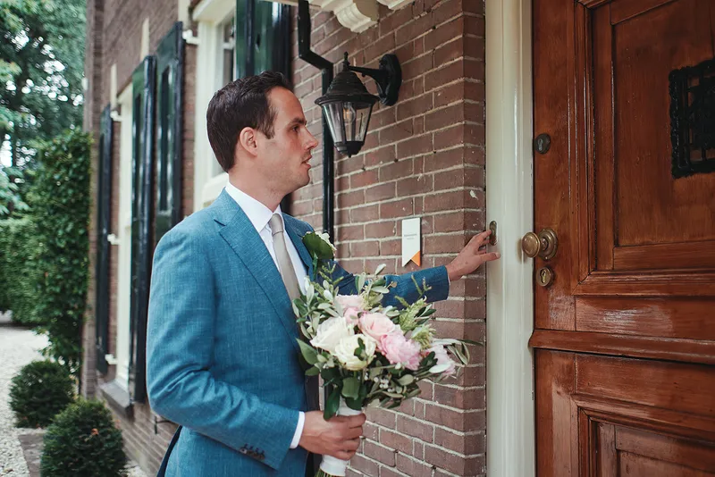 Niels belt aan bij de voordeur, met het boeket in zijn hand