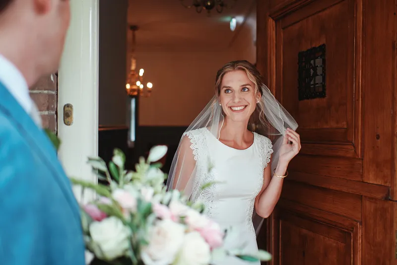 Karien kijkt lachend door de open deur naar Niels