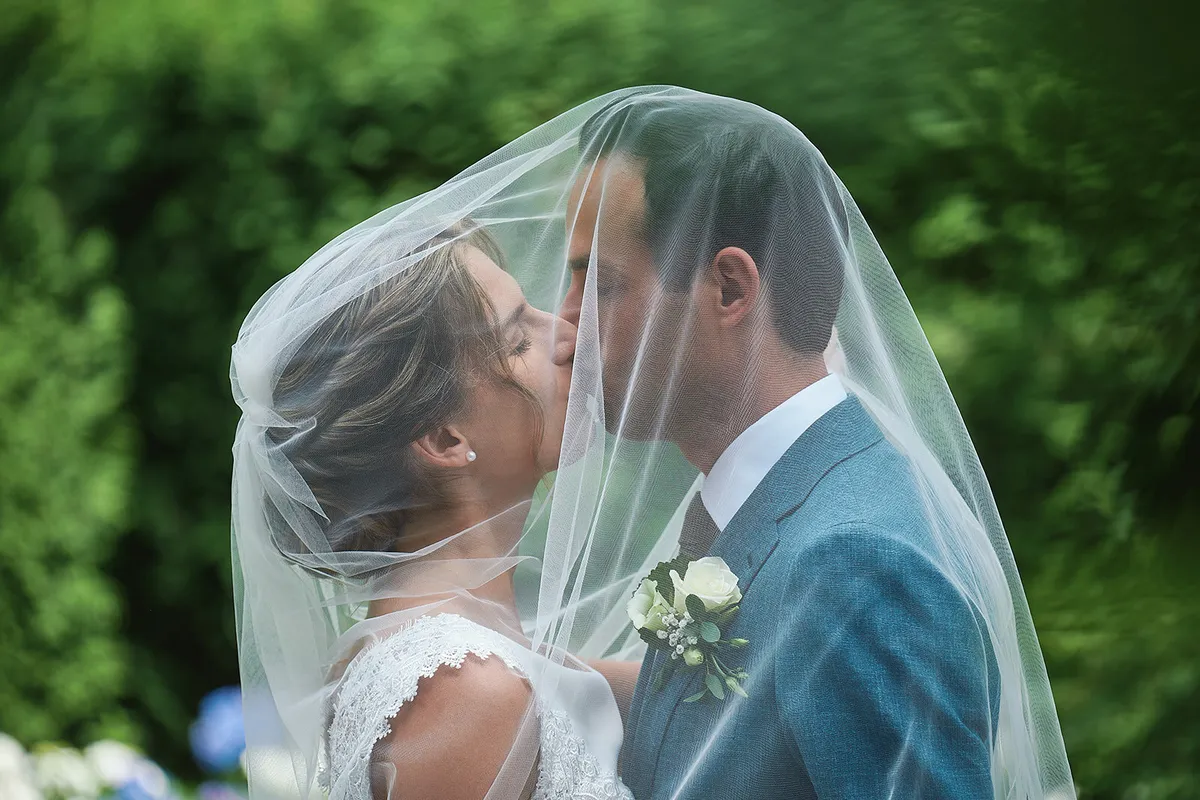 Karien en Niels kussen onder de doorzichtige sluier