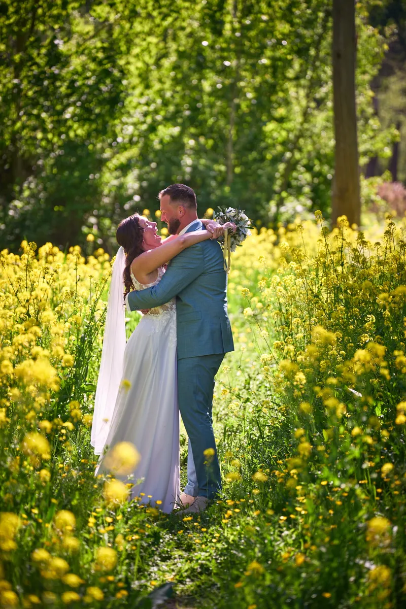 Michelle en Barrie omhelzen elkaar tussen de gele bloemen