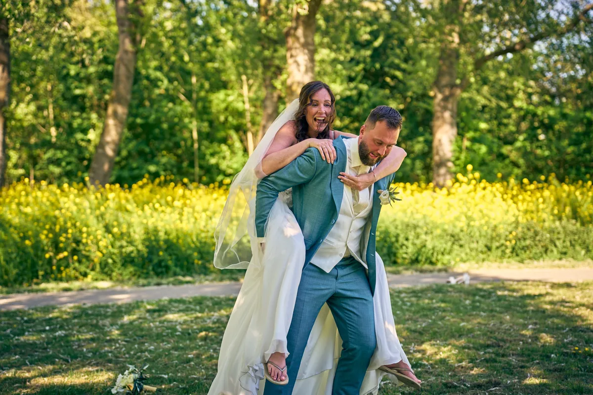 Michelle springt lachend op de rug van Barrie in het park