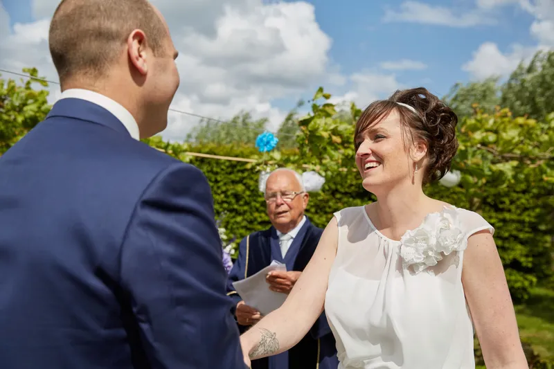 Marina lacht naar Erik, de trouwambtenaar op de achtergrond