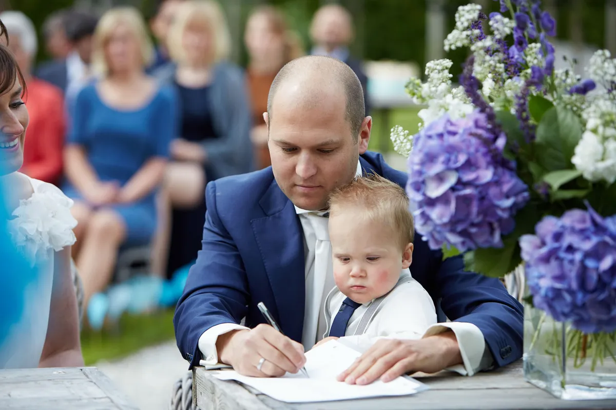 Erik tekent het register met hun zoontje op schoot