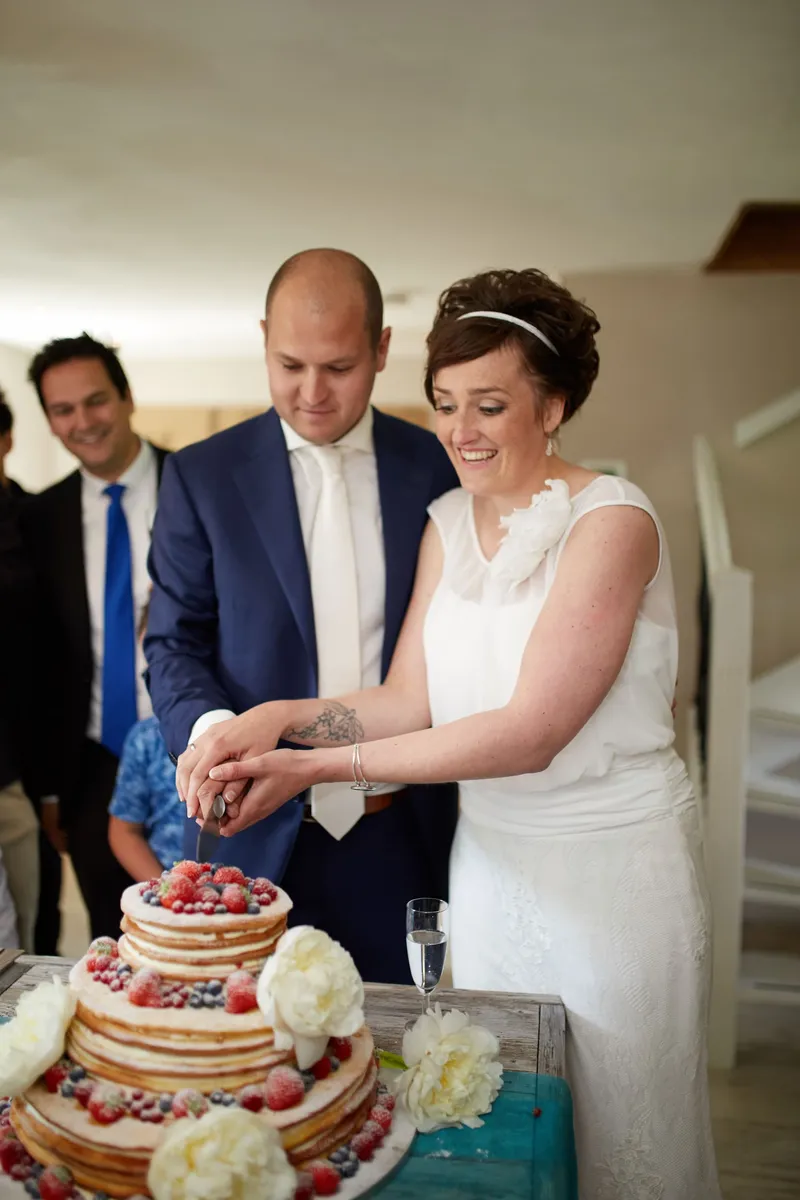 Marina en Erik snijden de taart aan, de gasten kijken toe