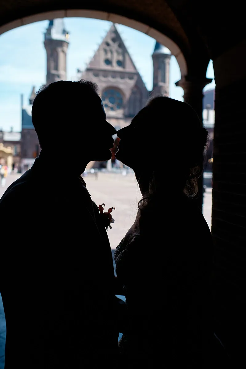 Neomi en Michael kussen als silhouet in de poort, met de Ridderzaal erachter