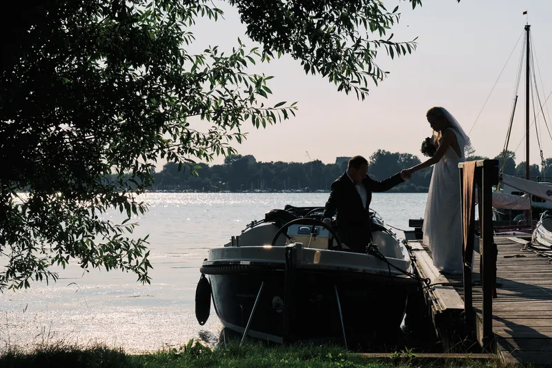Het bruidspaar in tegenlicht bij de sloep, met de Kralingse Plas op de achtergrond