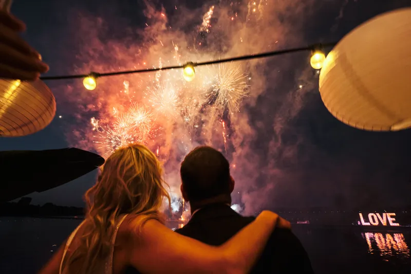 Het bruidspaar kijkt van het terras naar het vuurwerk boven de plas
