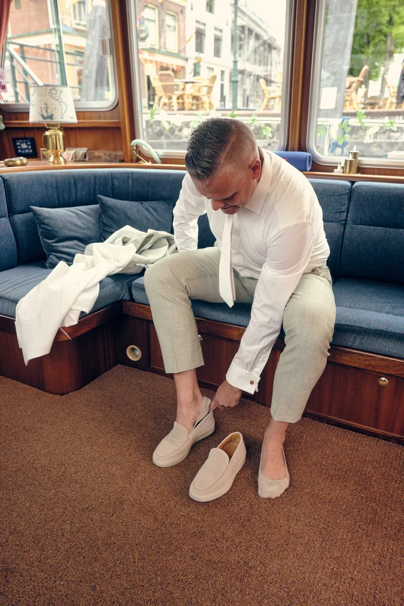 Marco trekt zijn schoenen aan op de bank van de boot
