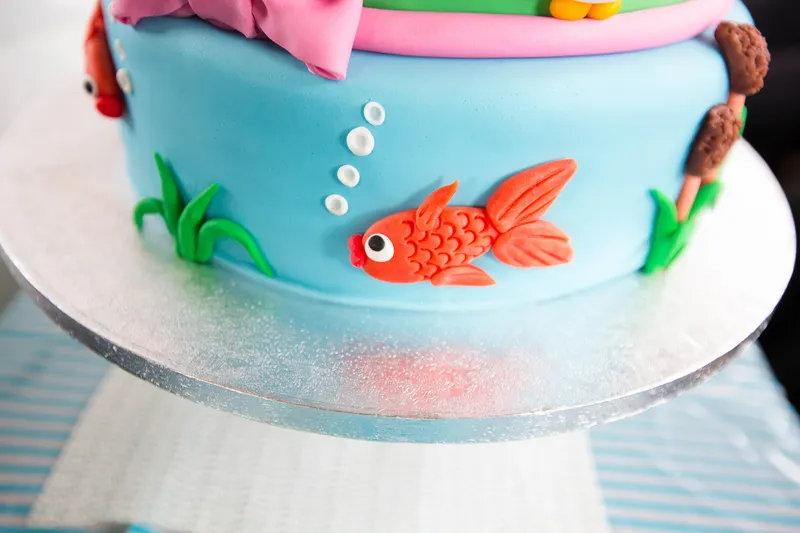 Een oranje visje van fondant op de taart