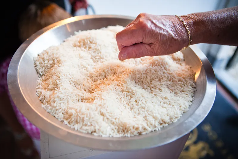 Een hand pakt rijst uit een grote schaal