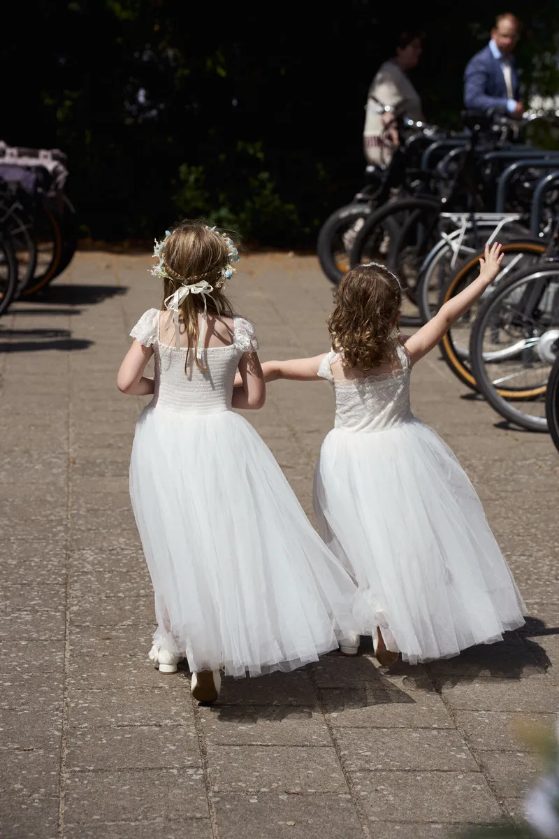 Twee bloemenmeisjes rennen over het terras van AA-Zicht