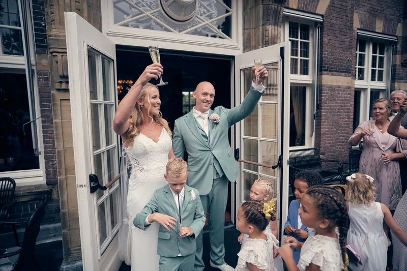 Kim en Dennis proosten in de deuropening, met de kinderen erbij