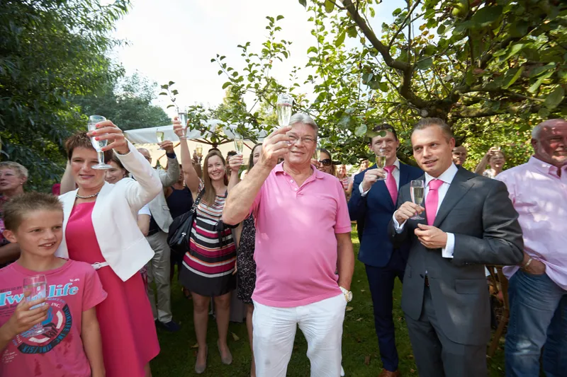 De gasten heffen het glas en juichen in de tuin