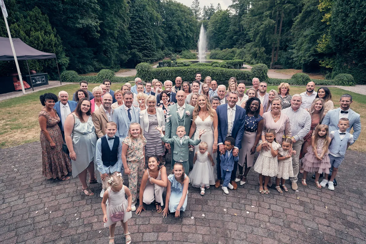 De groepsfoto met alle gasten in de kasteeltuin, van bovenaf