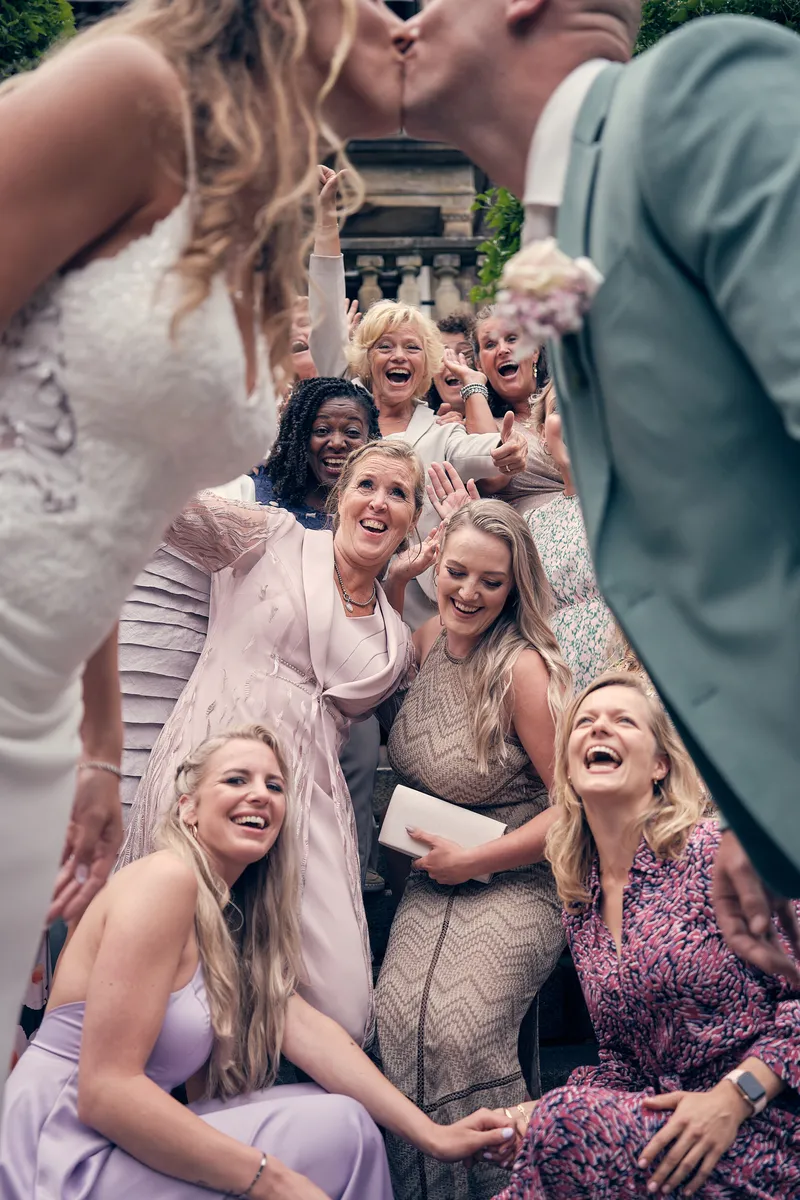 Kim lacht met haar vriendinnen, terwijl ze Dennis kust