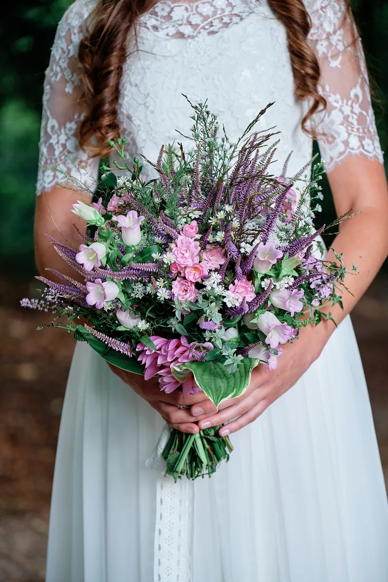 Het boeket met paarse bloemen voor de kanten jurk