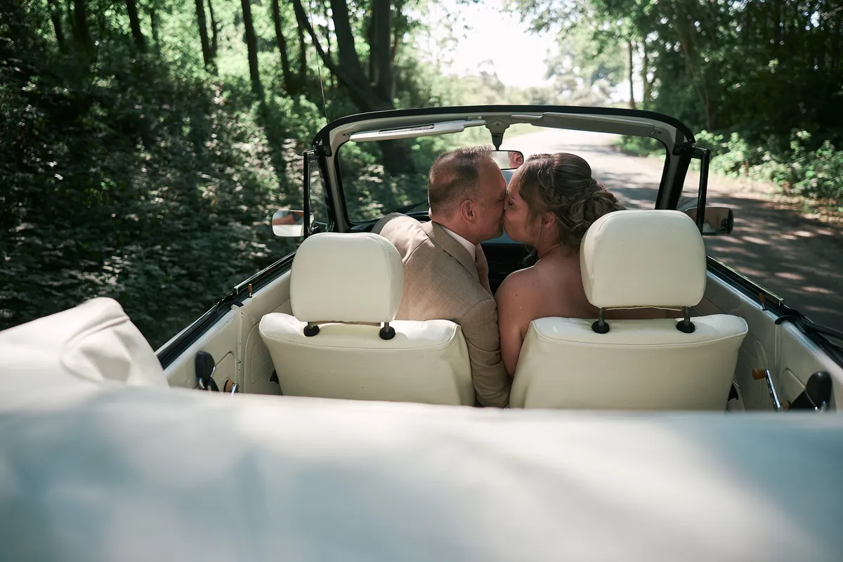 Mirjam en Jorg kussen elkaar achter in de Kever cabrio