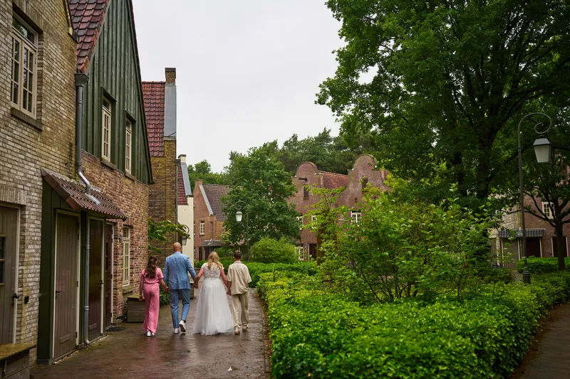 Het gezin loopt in de verte door een groen straatje tussen de huisjes van Bosrijk
