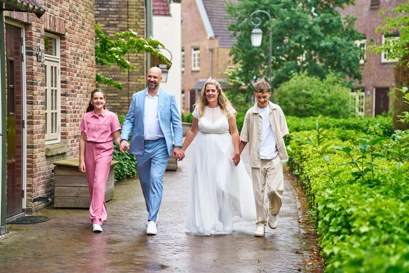 Annemarie en Jan lopen hand in hand met hun zoon en dochter over de natte keien