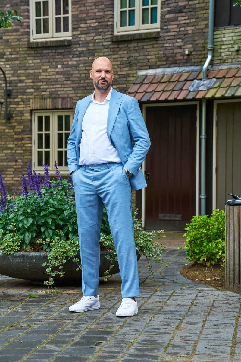 Jan in zijn lichtblauwe pak voor een groene deur