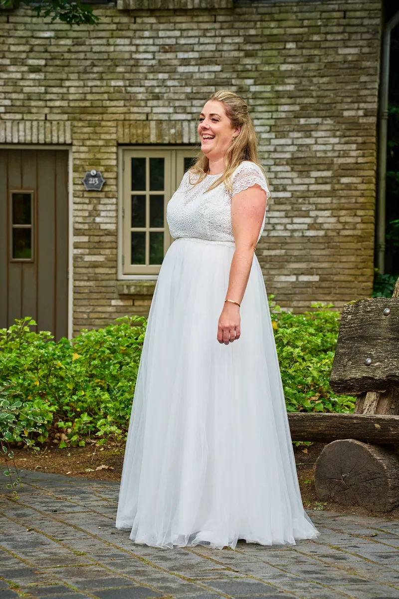 Annemarie in haar trouwjurk voor een bakstenen huisje