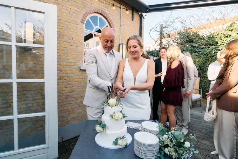Danitsja en Brian snijden de taart aan op het terras van De Brasserij
