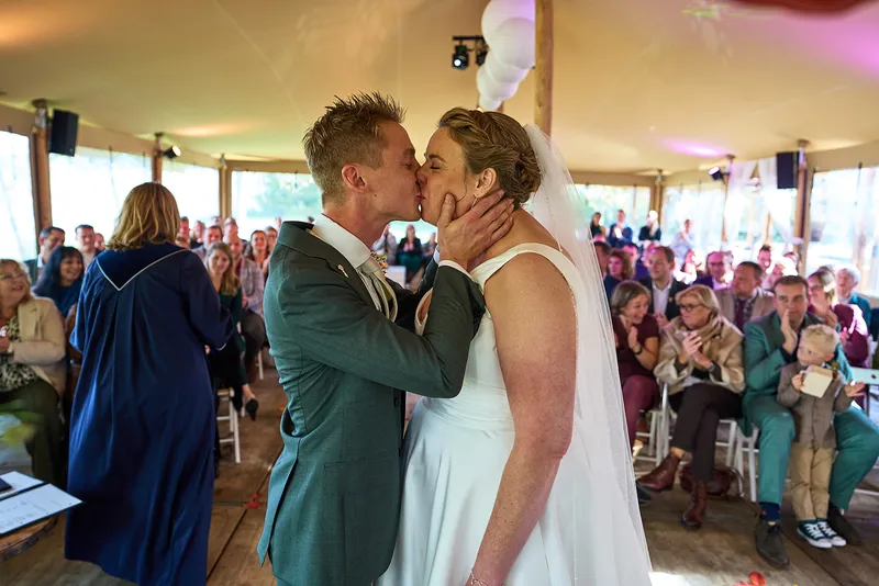 Karlijn en Glenn kijken elkaar aan onder de rode stof in de tent