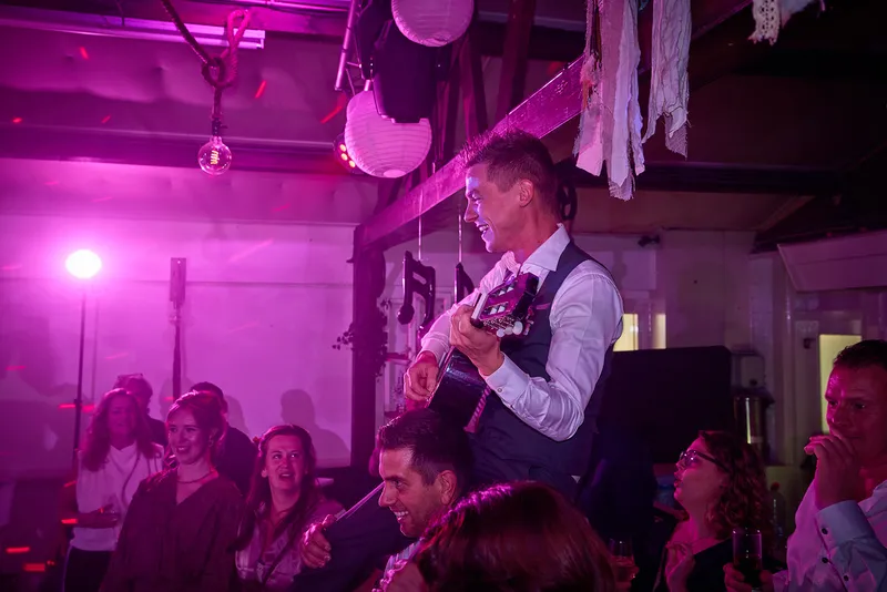 Een gast speelt gitaar op de schouders van een ander