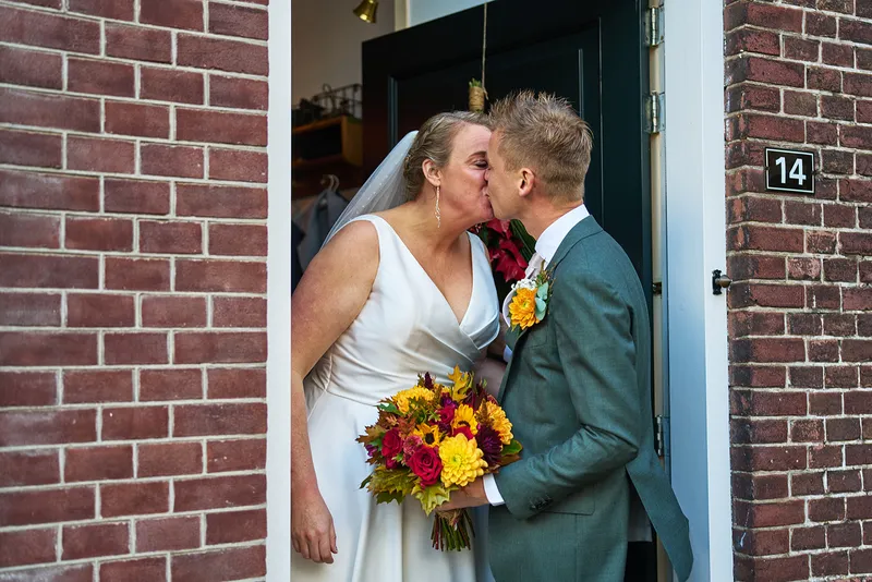 Karlijn en Glenn kussen in de deuropening bij hun first look