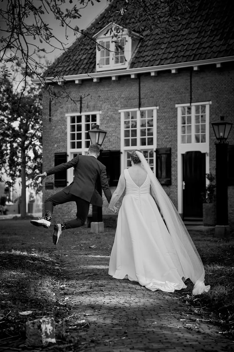 Zwart-wit: Karlijn en Glenn rennen hand in hand weg, de sluier erachteraan