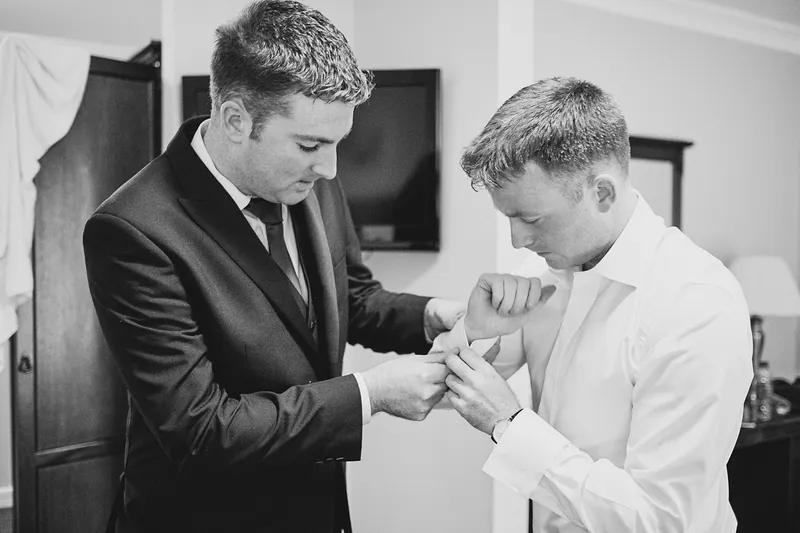 Shane krijgt hulp met zijn manchetknopen, in zwart-wit