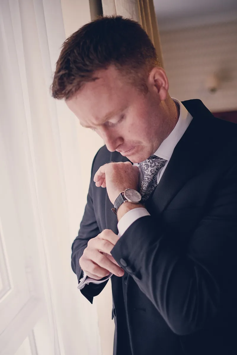 Shane kijkt op zijn horloge bij het raam