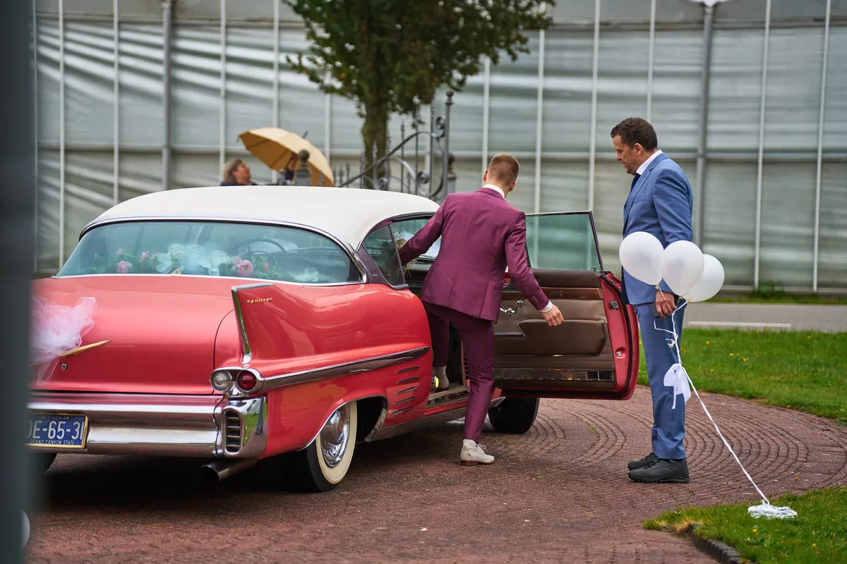 Tom stapt uit de roze Cadillac met witte ballonnen