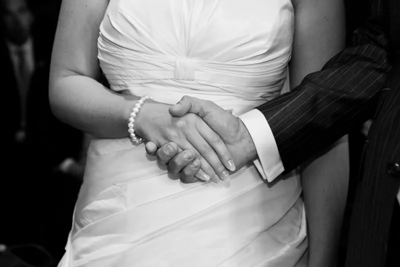 Jorinda en Gerben geven elkaar de hand tijdens de ceremonie, in zwart-wit