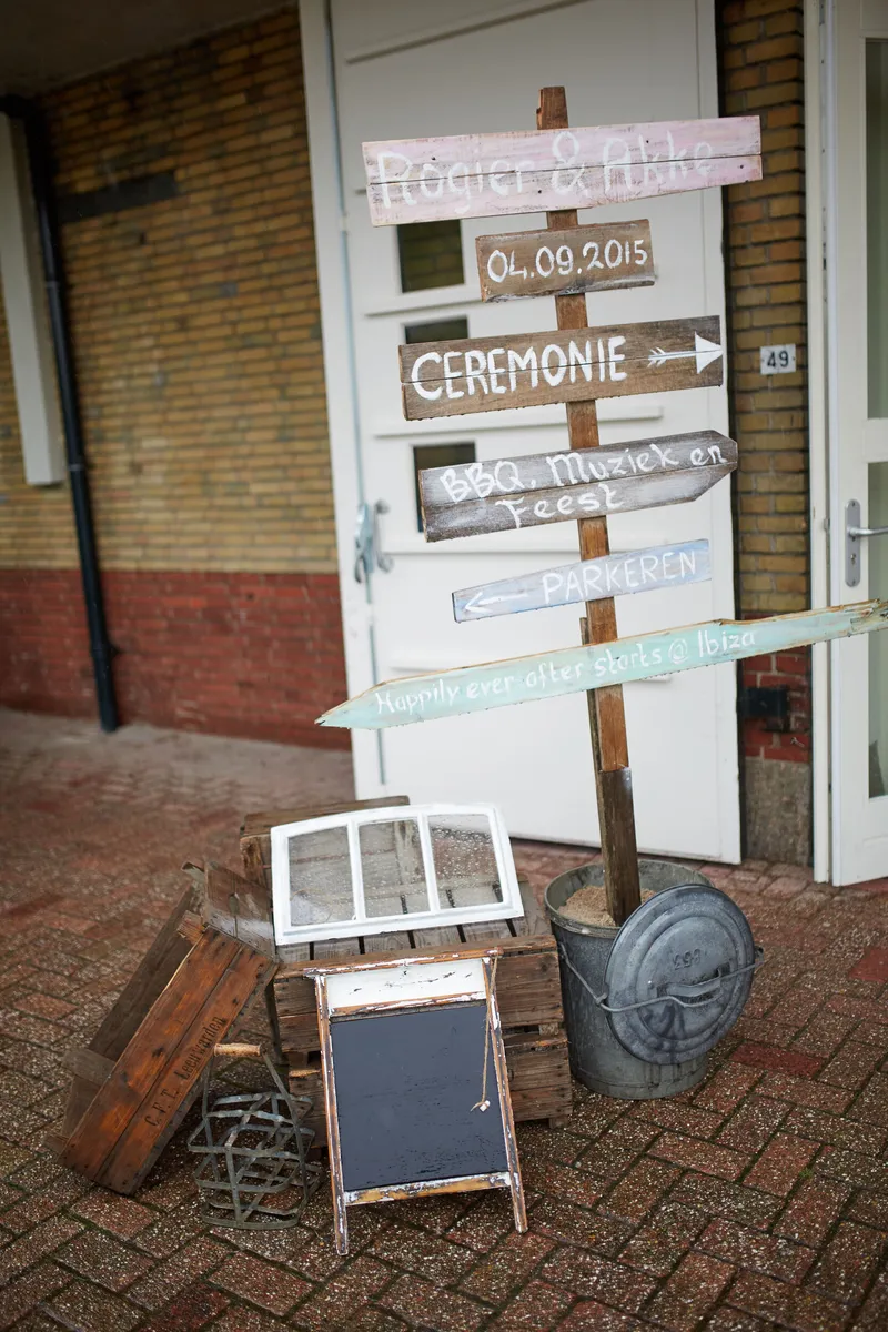 Een houten wegwijzer met hun voornamen en de datum wijst naar de ceremonie