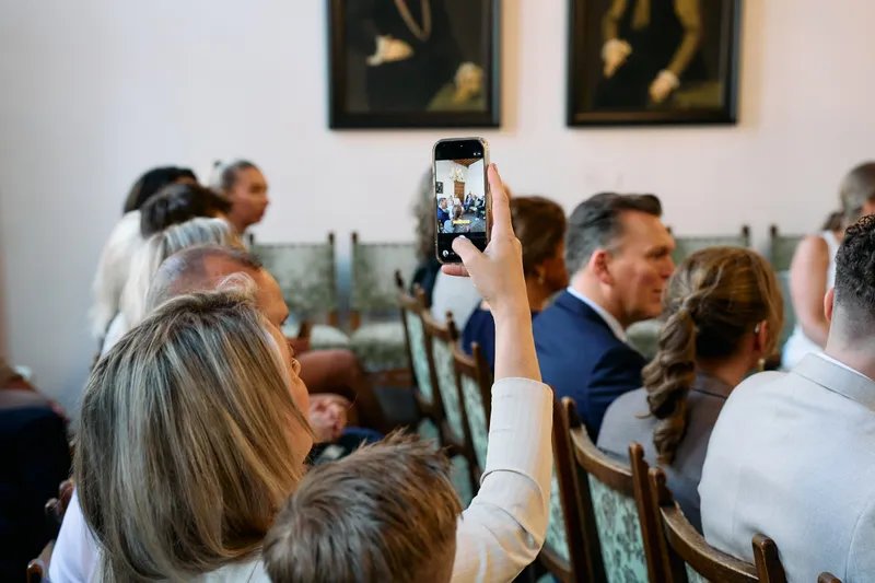Een gast filmt met zijn telefoon in de trouwzaal