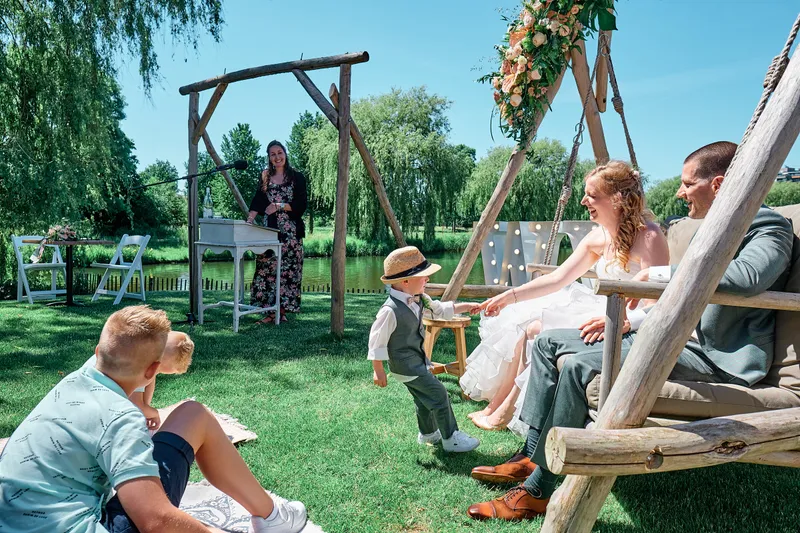 Ylona en Wouter op een houten schommel, de gasten op het gras