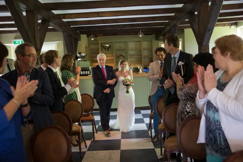 Liza komt binnen met haar vader, de gasten kijken toe
