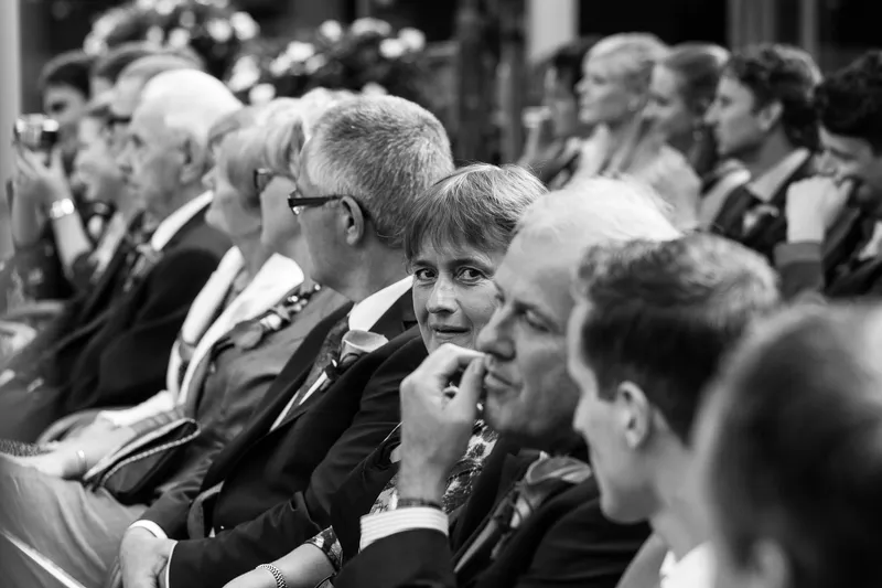 Gasten luisteren naar de ceremonie op Boerderij Dennisse, in zwart-wit