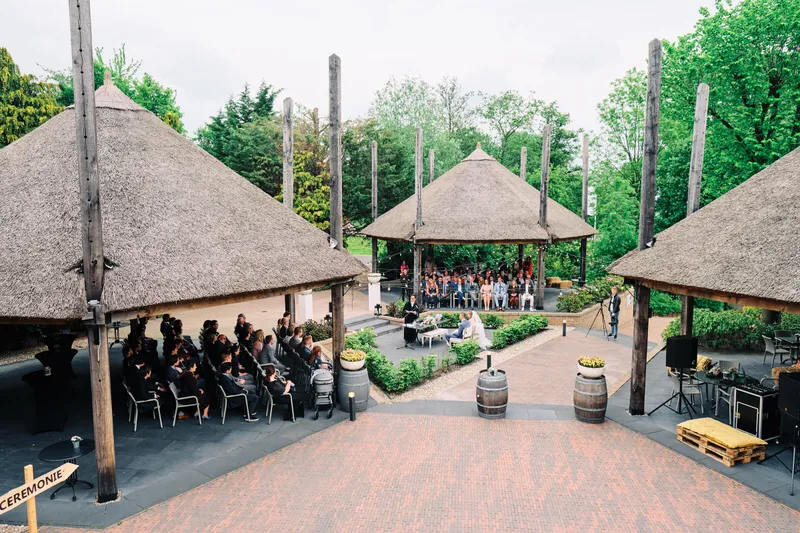 De rieten overkapping met de gasten in de tuin