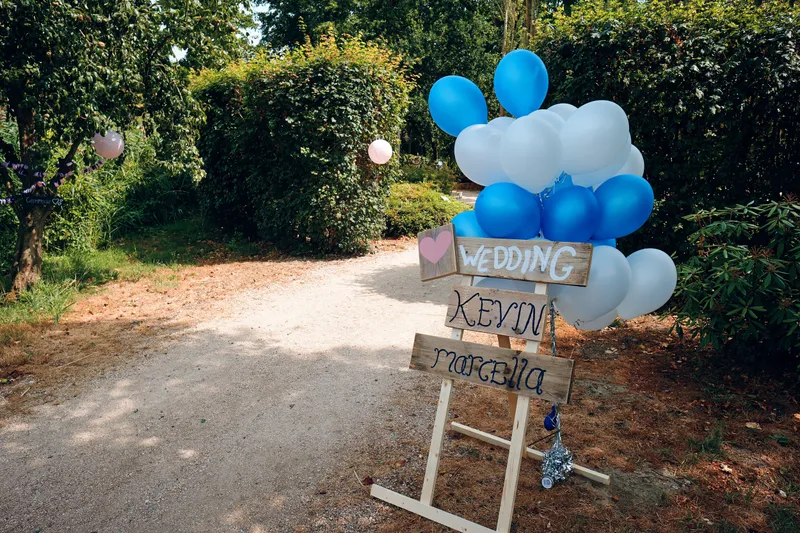 Het welkomstbord met blauwe en witte ballonnen bij de ingang van Vida