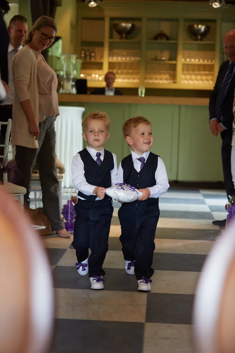 Twee jongetjes lopen in pak door de zaal