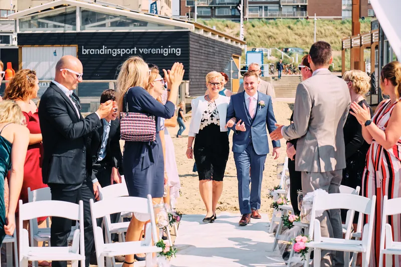 De gasten op witte stoelen in het zand